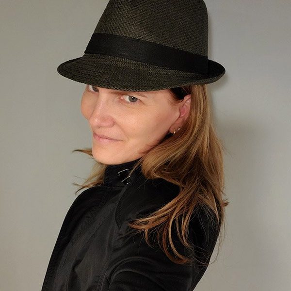 Kimberly Amato with a hat and black jacket looking at the camera over her left shoulder.